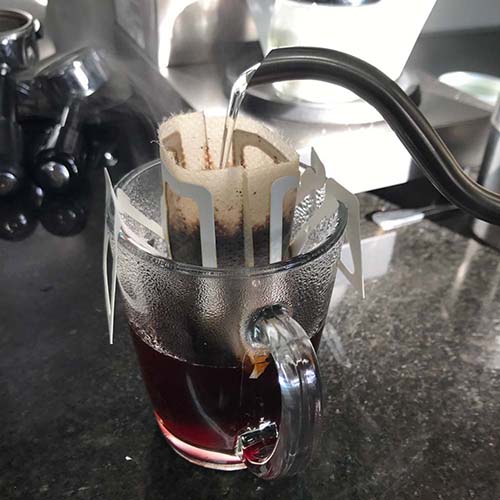 A Beanz Drip disposable bag hanging on a cup while hot water is poured, demonstrating easy brewing.