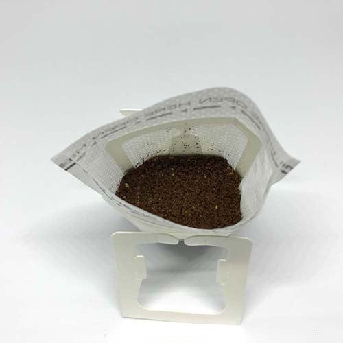 Freshly ground coffee inside a Beanz Drip disposable drip bag, shown from a unique angle.