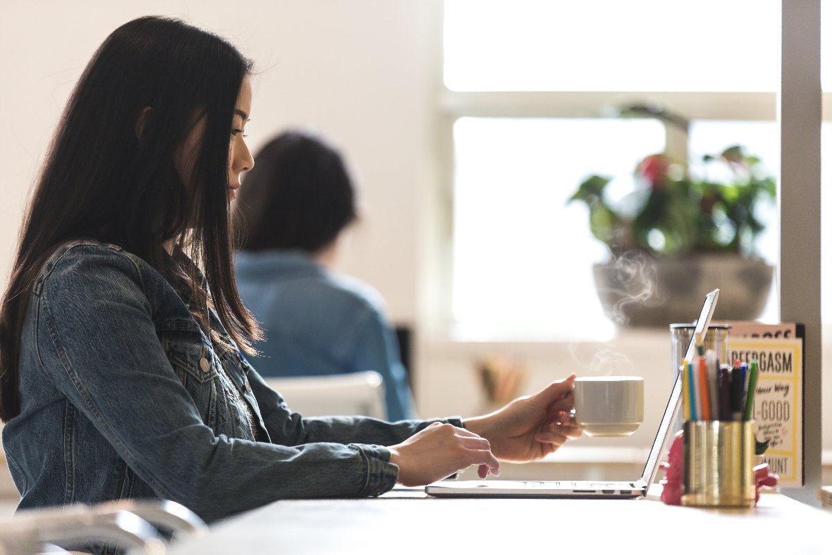 A woman working in an office, enjoying Beanz Drip coffee for a productive day.