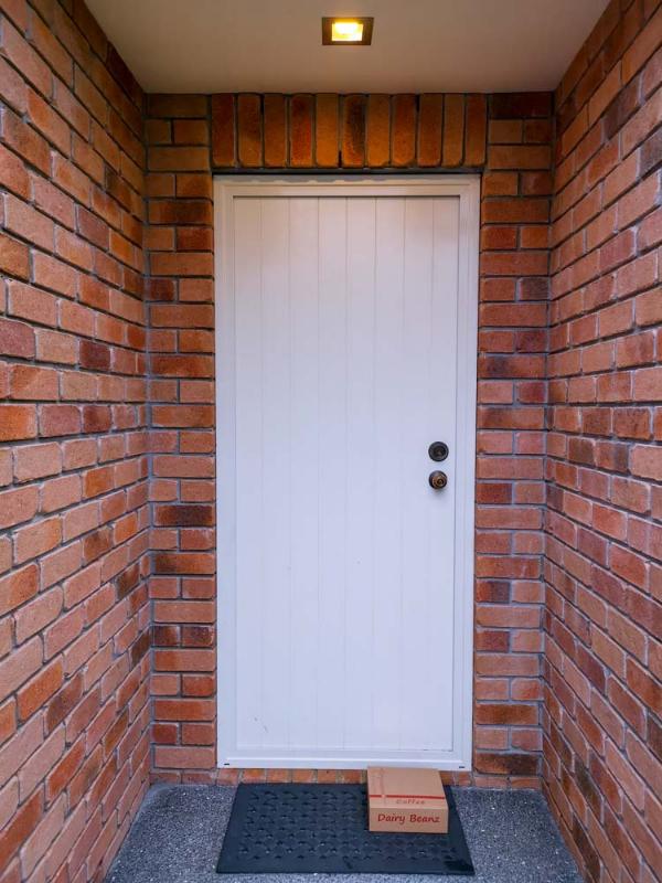 A Dairy Beanz coffee box delivered at the front doorstep of a beautiful house, symbolizing roast-to-order freshness and free shipping nationwide.