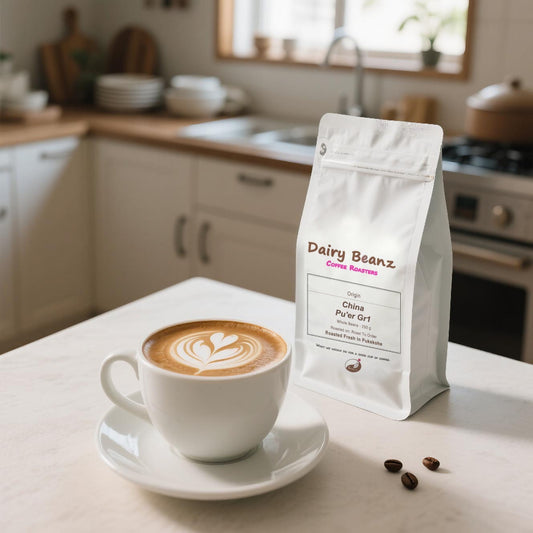 Dairy Beanz China Yunnan Pu'Er  Simao GR1 coffee in a minimalist package on a kitchen island with scattered beans and a latte topped with rosetta art in a modern kitchen.