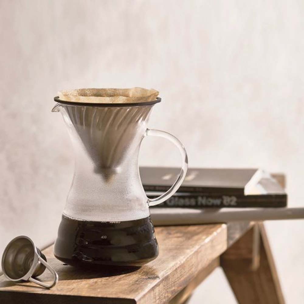 Use Hario V60 Pour Over Decanter brewing coffee on a bench and there are books on the bench.