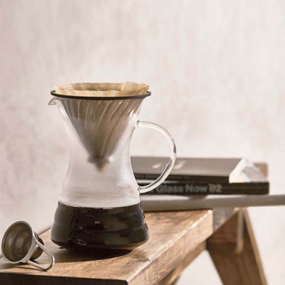 Use Hario V60 Pour Over Decanter brewing coffee on a bench and there are books on the bench.